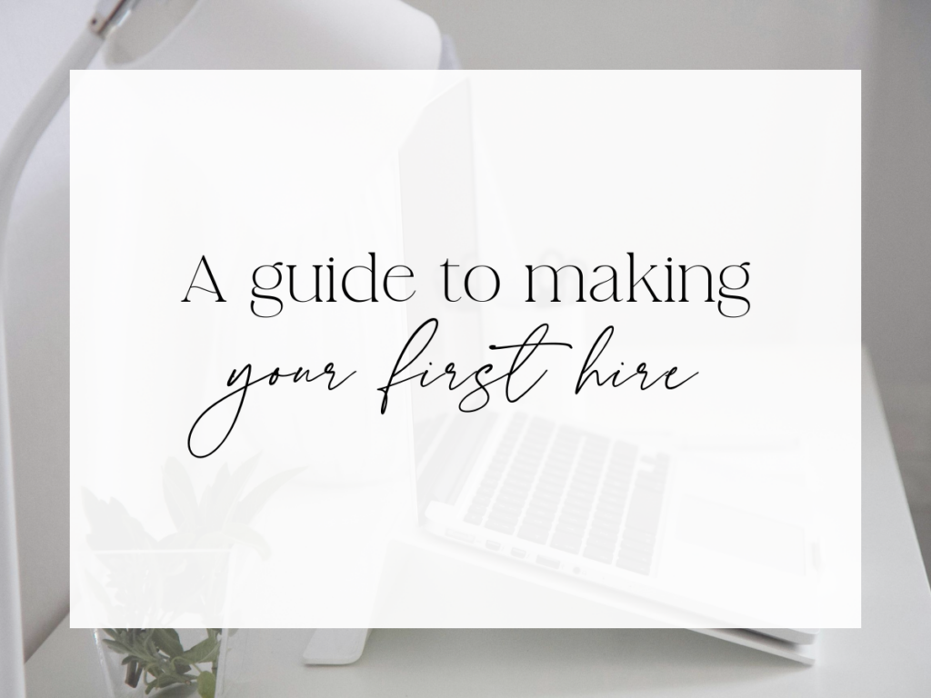 Clean, neutral workspace with a laptop, desk lamp, and small plant. Over a white overlay, the text reads: “A guide to making your first hire.”
