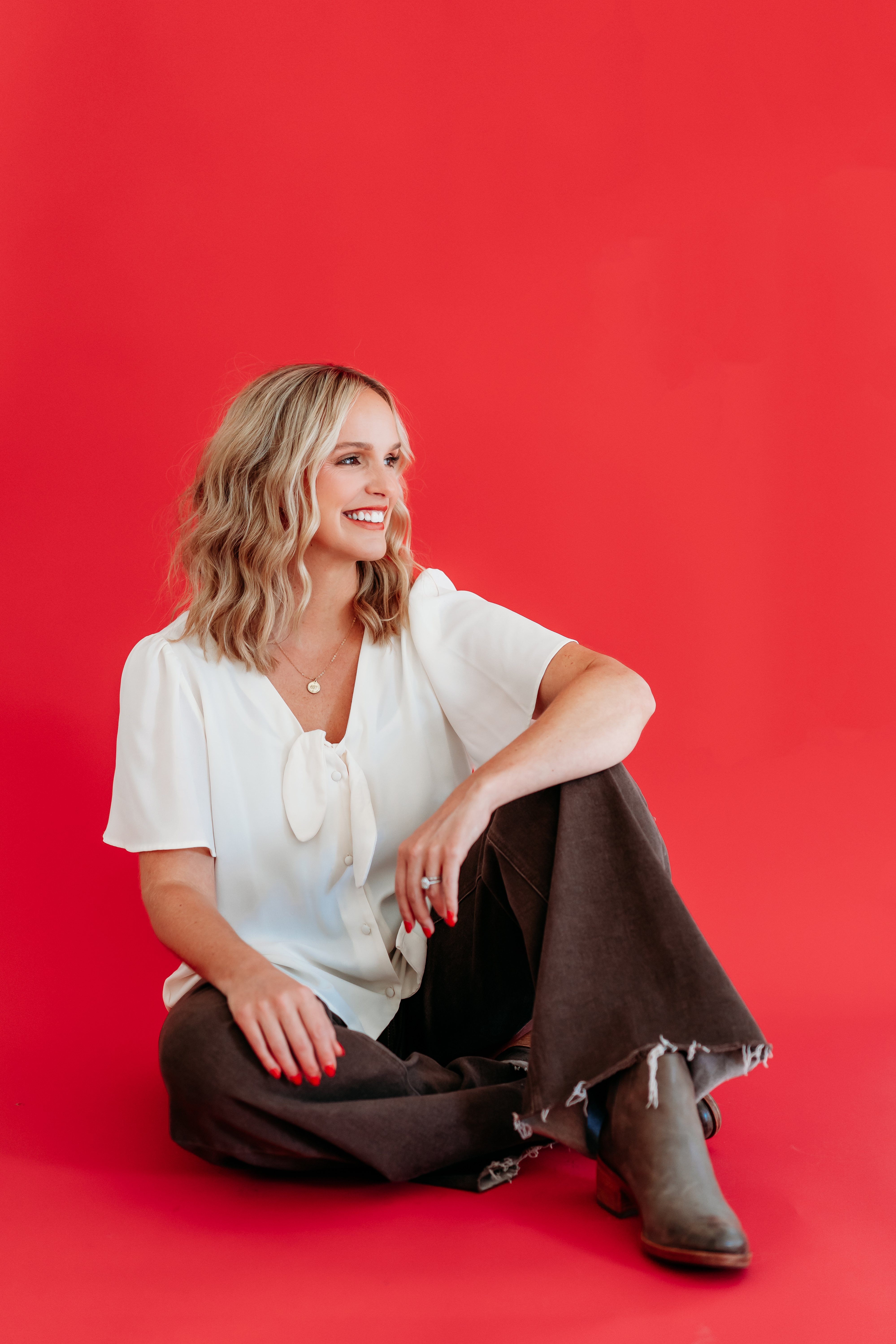 Lindsay Bowden sitting with a red background telling a Teacher side hustle success story: making money as a teacher with digital products